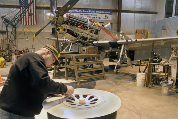 Jim Mason carefully sands a hub for one of Gunfighter’s three wheels. The P-51 Mustang built during World War II is on display at the Council Bluffs Municipal Airport and can be seen at airshows. Photo by Mike Whye